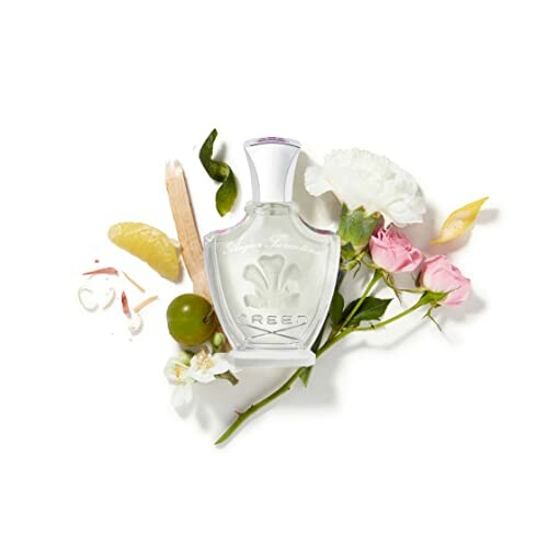 Creed perfume bottle surrounded by flowers and fruits.
