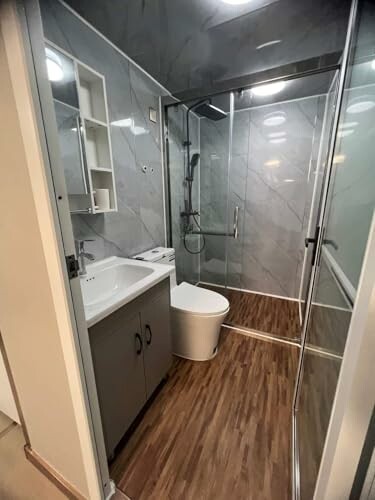 Modern bathroom with glass shower, sink, and toilet.