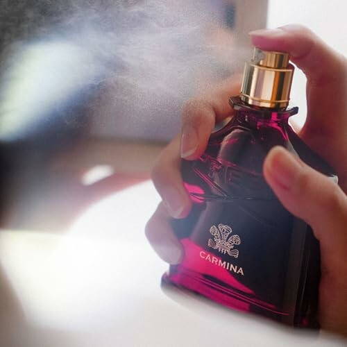 Person spraying perfume from a red bottle.